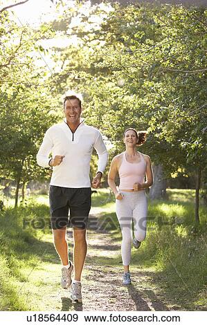 Stock Photo - Middle Aged Couple Jogging In Park. Fotosearch
