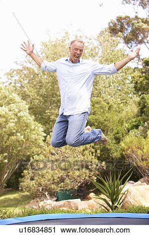 Middle Aged Man Jumping On Trampoline In Garden View Large Photo Image Stock Image - Middle Aged Man Jumping On Trampoline In Garden. Fotosearch