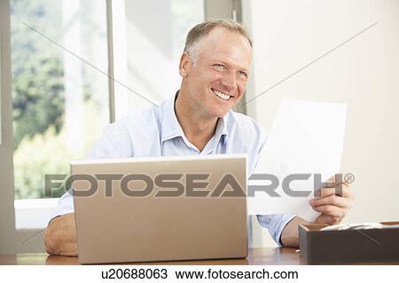 Stock Image - Middle Aged Man Using Laptop At Home. Fotosearch