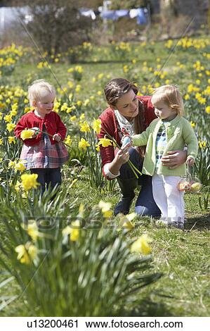 Stock Image - Mother And Children In Daffodil Field With Decorated Easter Eggs. Fotosearch