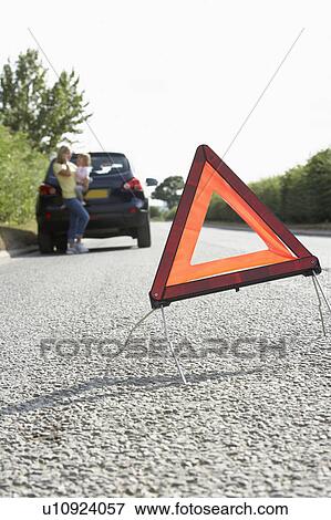 Stock Photo - Mother And Daughter Broken Down On Country Road With Hazard Warning Sign In Foreground. Fotosearch