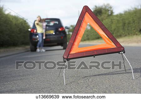 Stock Photo - Mother And Daughter Broken Down On Country Road With Hazard Warning Sign In Foreground. Fotosearch