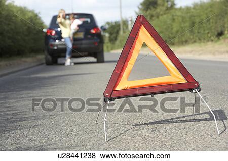 Stock Photo - Mother And Daughter Broken Down On Country Road With Hazard Warning Sign In Foreground. Fotosearch