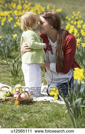 Stock Image - Mother And Daughter In Daffodil Field With Decorated Easter Eggs. Fotosearch
