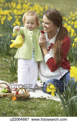 Stock Photo - Mother And Daughter In Daffodil Field With Decorated Easter Eggs. Fotosearch