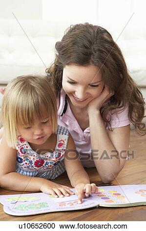 Stock Image - Mother And Daughter Learning To Read At Home. Fotosearch