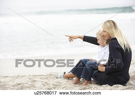 Stock Photo - Mother And Daughter On Holiday Sitting On Winter Beach. Fotosearch