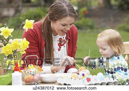 Stock Image - Mother And Daughter Painting Easter Eggs In Gardens. Fotosearch