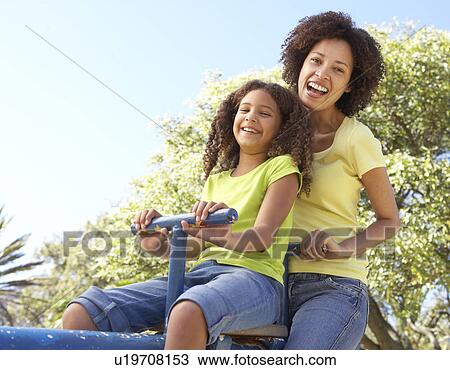 Mother And Daughter Riding On Seesaw In Park View Large Photo Image Stock Image - Mother And Daughter Riding On Seesaw In Park. Fotosearch