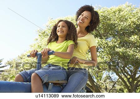 Stock Photo - Mother And Daughter Riding On Seesaw In Park. Fotosearch