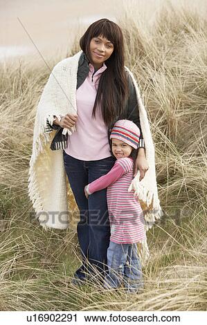 Mother And Daughter Wrapped In Blanket Amongst Dunes On Winter Beach View Large Photo Image Stock Image - Mother And Daughter Wrapped In Blanket Amongst Dunes On Winter Beach. Fotosearch
