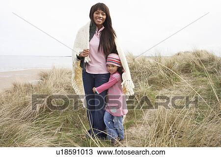 Mother And Daughter Wrapped In Blanket Amongst Dunes On Winter Beach View Large Photo Image Stock Image - Mother And Daughter Wrapped In Blanket Amongst Dunes On Winter Beach. Fotosearch