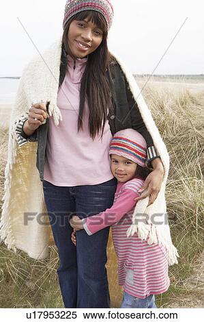 Stock Photography - Mother And Daughter Wrapped In Blanket Amongst Dunes On Winter Beach. Fotosearch