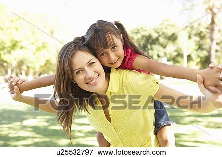 Mother Giving Daughter Ride On Back In Park View Large Photo Image Stock Photo - Mother Giving Daughter Ride On Back In Park. Fotosearch