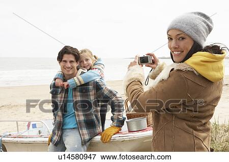 Stock Photo - Mother Taking Family Photograph On Winter Beach. Fotosearch