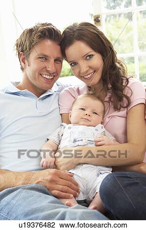 Stock Image - Parents Cuddling Newborn Baby Boy At Home. Fotosearch