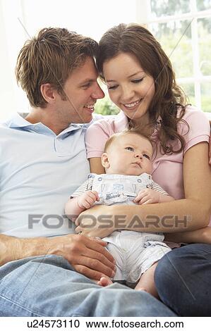 Stock Image - Parents Cuddling Newborn Baby Boy At Home. Fotosearch