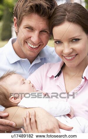 Stock Image - Parents Cuddling Newborn Baby Boy Outdoors At Home. Fotosearch