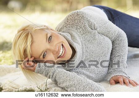 Stock Image - Portrait Of Attractive Young Woman Relaxing On Grass. Fotosearch
