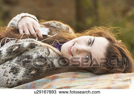 Stock Image - Portrait Of Beautiful Teenage Girl Outdoors Listening To MP3 Player In Autumn Landscape. Fotosearch