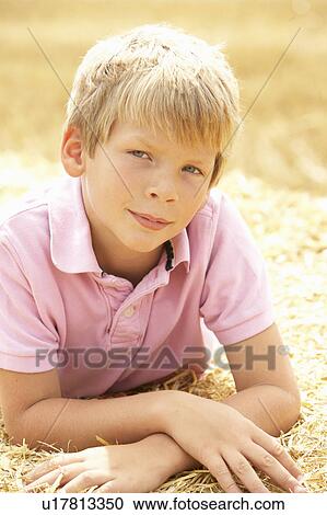 Stock Image - Portrait Of Boy Laying In Summer Harvested Field. Fotosearch