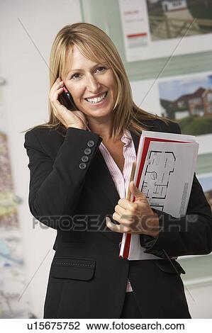 Stock Image - Portrait Of Female Estate Agent In Office On Phone. Fotosearch