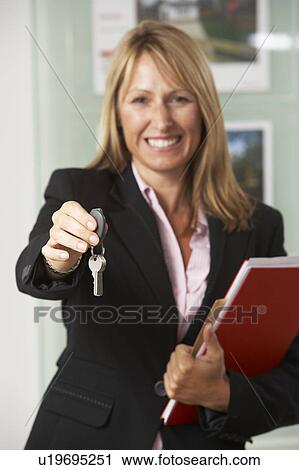 Portrait Of Female Estate Agent In Office Handing Over Keys View Large Photo Image Stock Image - Portrait Of Female Estate Agent In Office Handing Over Keys. Fotosearch