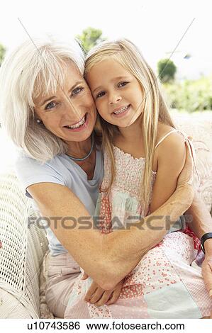Stock Photograph - Portrait Of Grandmother With Granddaughter Relaxing Together On Sofa. Fotosearch