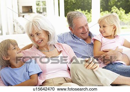 Stock Image - Portrait Of Grandparents With Grandchildren Relaxing Together On Sofa. Fotosearch