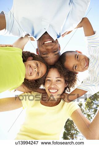 Stock Photo - Portrait of Happy Family Looking Down Into Camera In Park. Fotosearch