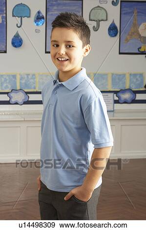 Stock Photo - Portrait Of Male Primary School Pupil Standing In Classroom. Fotosearch