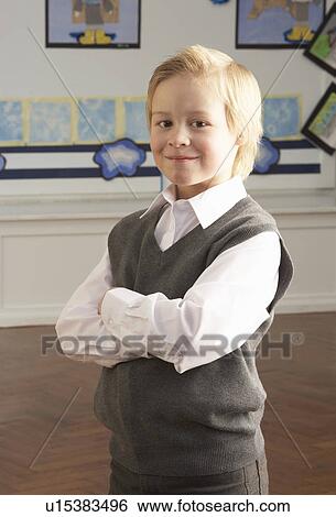 Stock Photograph - Portrait Of Male Primary School Pupil Standing In Classroom. Fotosearch