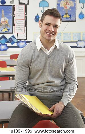 Portrait Of Male Teacher Sitting At Desk In Classroom View Large Photo Image Stock Photography - Portrait Of Male Teacher Sitting At Desk In Classroom. Fotosearch