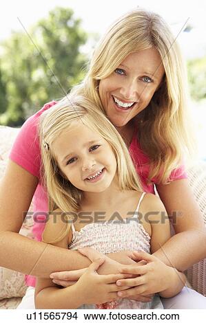Picture - Portrait Of Mother And Daughter Relaxing On Sofa. Fotosearch