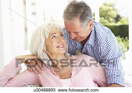 Stock Image - Portrait Of Senior Couple Relaxing Together On Sofa. Fotosearch