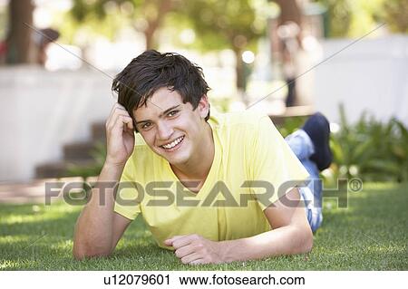 Stock Image - Portrait Of Teenage Boy Laying In Park. Fotosearch