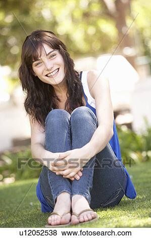 Stock Photo - Portrait Of Teenage Girl Sitting In Park. Fotosearch