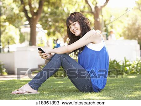 Portrait Of Teenage Girl Sitting In Park Using Mobile Phone View Large Photo Image Stock Image - Portrait Of Teenage Girl Sitting In Park Using Mobile Phone. Fotosearch