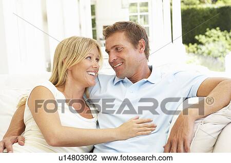 Stock Image - Portrait Of Young Couple Relaxing Together On Sofa. Fotosearch