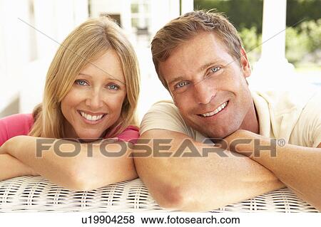 Stock Photo - Portrait Of Young Couple Relaxing Together On Sofa. Fotosearch