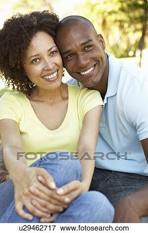 Portrait Of Young Couple Sitting In Park View Large Photo Image Stock Photo - Portrait Of Young Couple Sitting In Park. Fotosearch