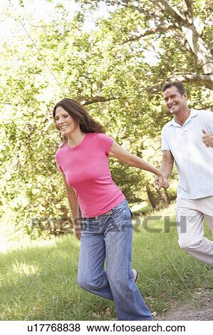 Portrait Of Young Couple Walking In Park View Large Photo Image Stock Photo - Portrait Of Young Couple Walking In Park. Fotosearch