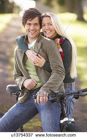 Portrait Of Young Couple With Cycle In Autumn Park View Large Photo Image Stock Photo - Portrait Of Young Couple With Cycle In Autumn Park. Fotosearch