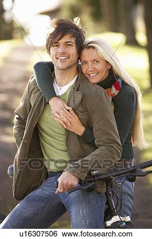 Stock Photograph - Portrait Of Young Couple With Cycle In Autumn Park. Fotosearch