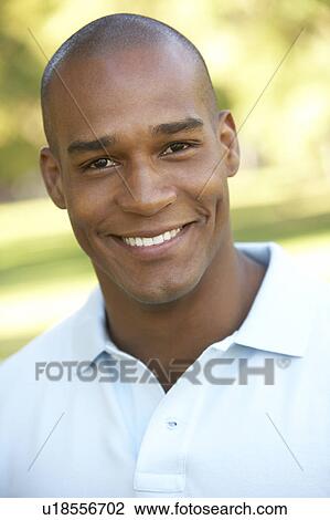 Stock Image - Portrait Of Young Man Sitting In Park. Fotosearch