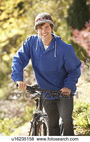 Stock Photo - Portrait Of Young Man With Cycle In Autumn Park. Fotosearch