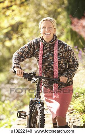 Stock Photo - Portrait Of Young Woman With Cycle In Autumn Park. Fotosearch