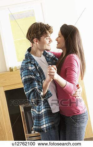 Stock Image - Romantic Young Couple Dancing Together In Living Room. Fotosearch