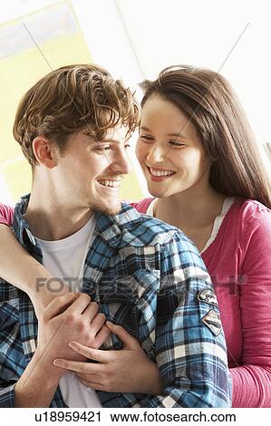 Stock Image - Romantic Young Couple Embracing In Living Room. Fotosearch