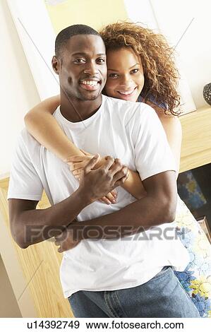 Stock Photo - Romantic Young Couple Embracing In Living Room. Fotosearch